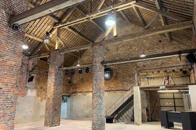 Parking en gravier entouré d'arbres et de bâtiments en briques sous un ciel partiellement nuageux.