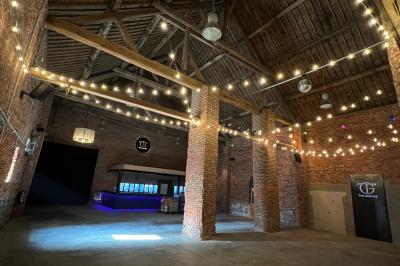 Parking en gravier entouré d'arbres et de bâtiments en briques sous un ciel partiellement nuageux.