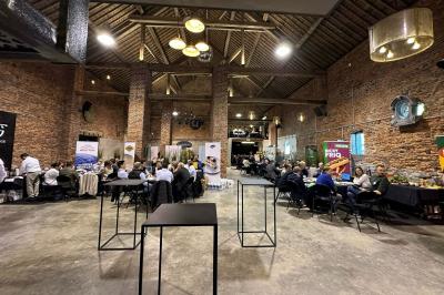 Parking en gravier entouré d'arbres et de bâtiments en briques sous un ciel partiellement nuageux.