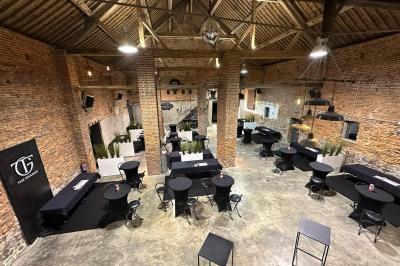 Parking en gravier entouré d'arbres et de bâtiments en briques sous un ciel partiellement nuageux.