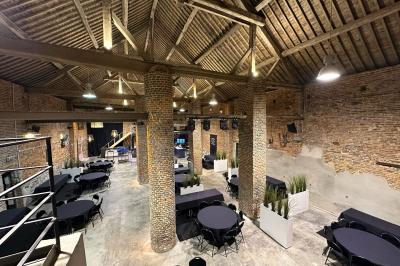 Parking en gravier entouré d'arbres et de bâtiments en briques sous un ciel partiellement nuageux.