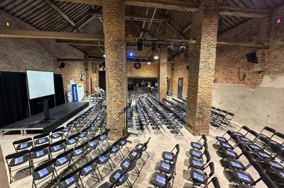 Parking en gravier entouré d'arbres et de bâtiments en briques sous un ciel partiellement nuageux.
