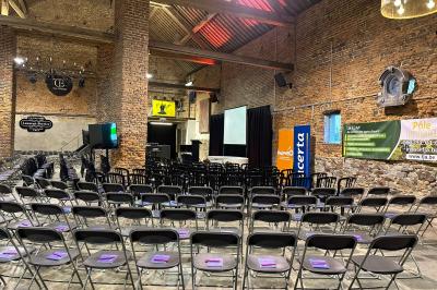 Parking en gravier entouré d'arbres et de bâtiments en briques sous un ciel partiellement nuageux.