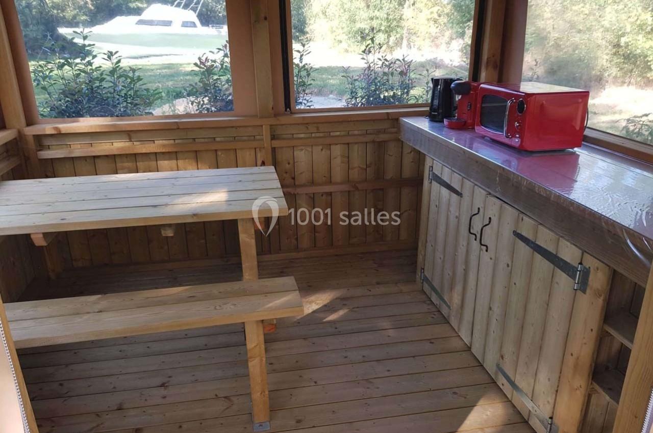 Abri en bois avec table de pique-nique, plan de travail équipé d'un micro-ondes rouge et d'une cafetière.
