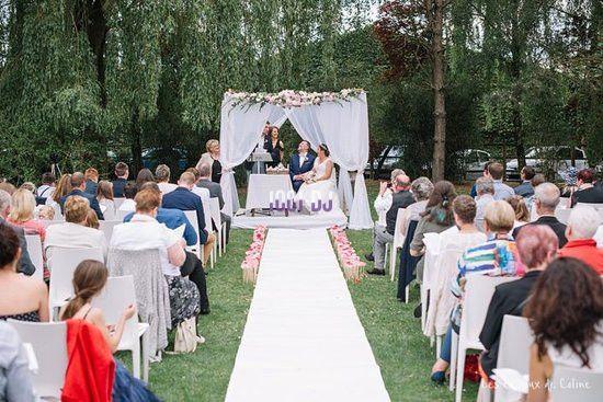 Cérémonie de mariage en extérieur avec des invités assis, une allée centrale et un autel décoré de fleurs.