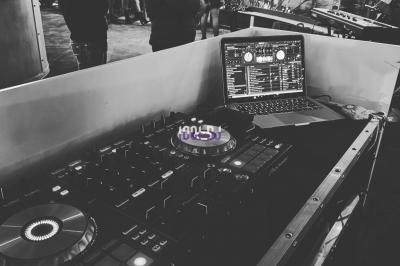 Table de mixage éclairée par des lumières colorées dans une ambiance de soirée ou de concert.