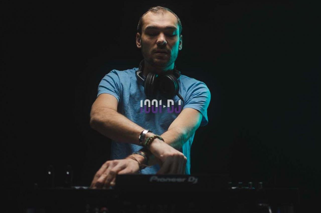 Un DJ concentré mixe de la musique sur une table de mixage dans un environnement sombre.