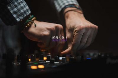 Portrait d'un homme souriant avec un éclairage tamisé sur fond sombre, un logo ’1001 DJ’ superposé au centre.