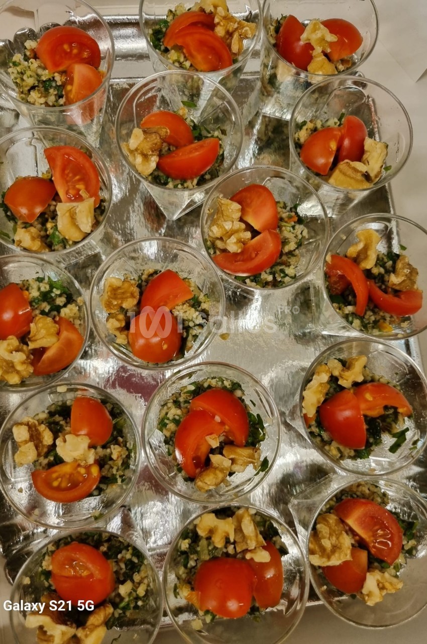 Verrines de taboulé garnies de tomates cerises et noix, disposées sur un plateau argenté.