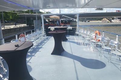 Miniature Location salle Paris 16 (Paris) - Bateau Le Rêve sur Seine #5 Pont supérieur d'un bateau aménagé avec des tables hautes et des chaises, amarré près d'une rive sous un ciel dégagé.