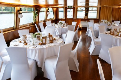 Miniature Location salle Paris 16 (Paris) - Bateau Le Rêve sur Seine #9 Un capitaine en uniforme utilise une radio dans la cabine d'un bateau, avec vue sur une rivière bordée d'arbres.