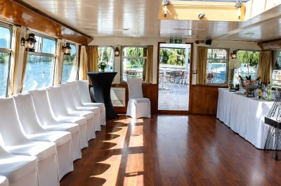 Miniature Location salle Paris 16 (Paris) - Bateau Le Rêve sur Seine #11 Un capitaine en uniforme utilise une radio dans la cabine d'un bateau, avec vue sur une rivière bordée d'arbres.