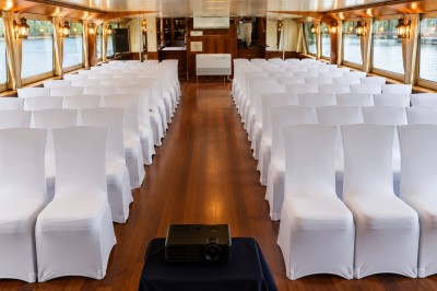 Miniature Location salle Paris 16 (Paris) - Bateau Le Rêve sur Seine #12 Un capitaine en uniforme utilise une radio dans la cabine d'un bateau, avec vue sur une rivière bordée d'arbres.
