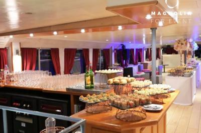 Miniature Location salle Paris 12 (Paris) - La Péniche Croisière de Bercy #7 Salle de réception sur une péniche avec tables rondes dressées, rideaux rouges et buffet de desserts au premier plan.