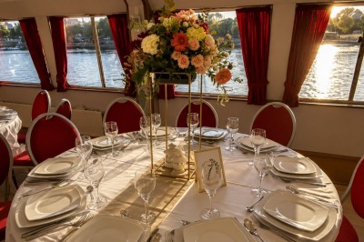 Miniature Location salle Paris 12 (Paris) - La Péniche Croisière de Bercy #10 Intérieur d'une salle spacieuse avec parquet, canapés colorés, tables rondes noires et rideaux rouges.