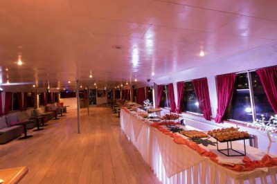 Miniature Location salle Paris 12 (Paris) - La Péniche Croisière de Bercy #11 Intérieur d'une salle spacieuse avec parquet, canapés colorés, tables rondes noires et rideaux rouges.