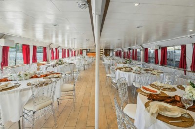 Miniature Location salle Paris 12 (Paris) - La Péniche Croisière de Bercy #15 Intérieur d'une salle spacieuse avec parquet, canapés colorés, tables rondes noires et rideaux rouges.