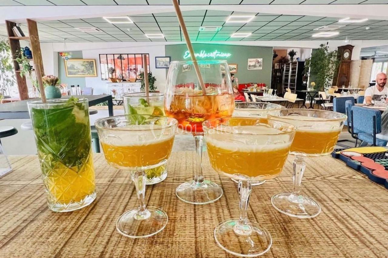 Un assortiment de cocktails colorés servis sur un comptoir en bois dans un espace lumineux et moderne.