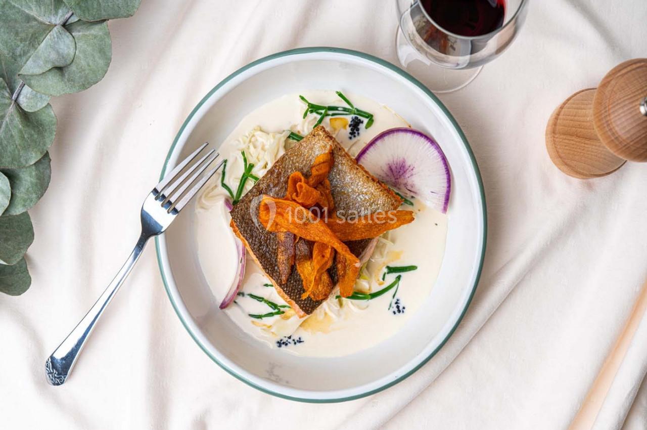 Assiette de poisson grillé avec peau croustillante, légumes, sauce crémeuse et chips de patate douce, vue de dessus.