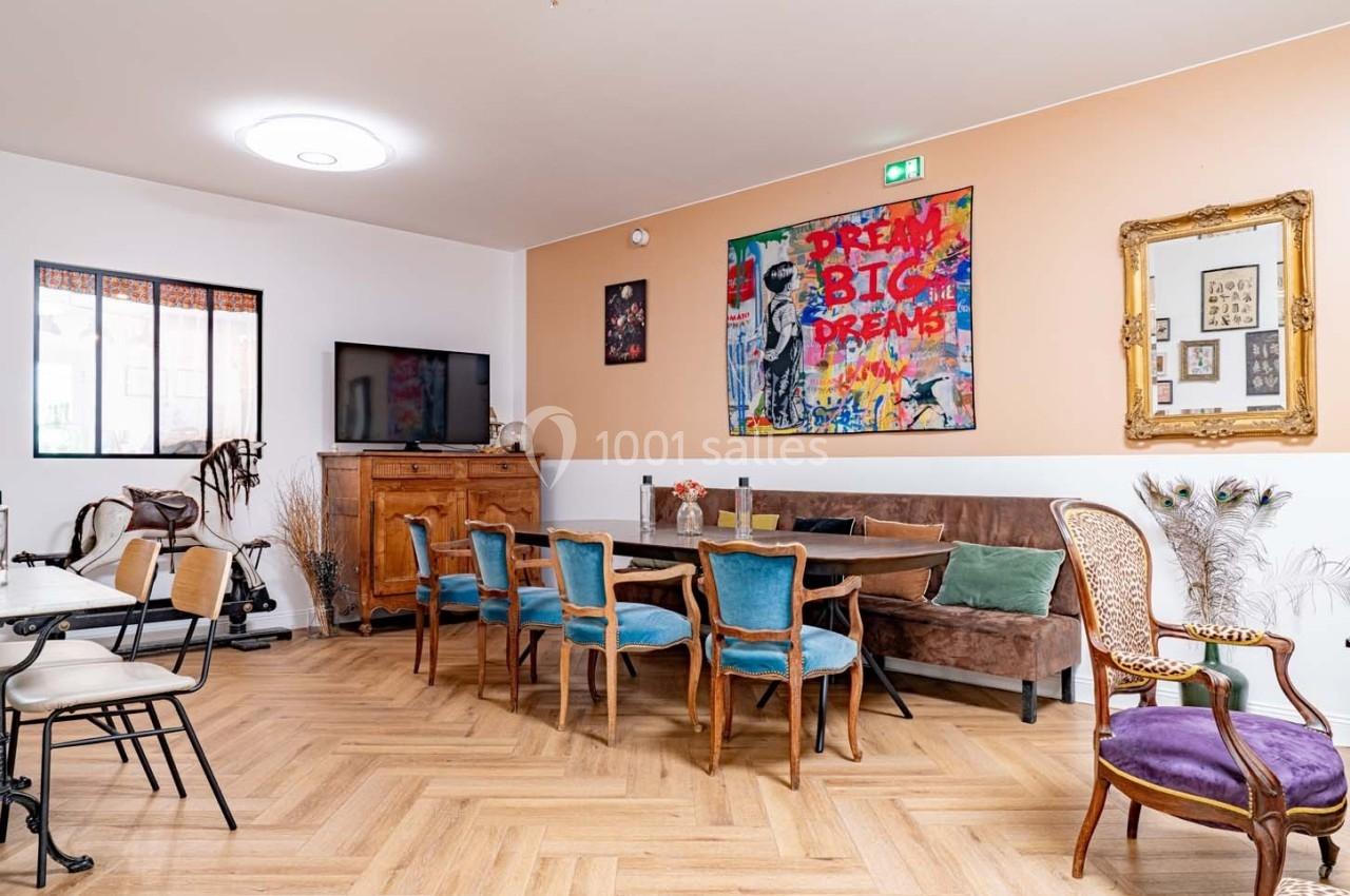 Salle à manger lumineuse avec table en bois, chaises colorées, parquet clair et décorations murales variées.