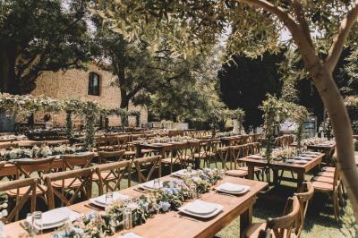 Un groupe de personnes en tenue de cérémonie tient des fumigènes colorés dans un champ ouvert.