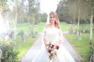 Un groupe de personnes en tenue de cérémonie tient des fumigènes colorés dans un champ ouvert.