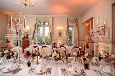 Un groupe de personnes en tenue de cérémonie tient des fumigènes colorés dans un champ ouvert.