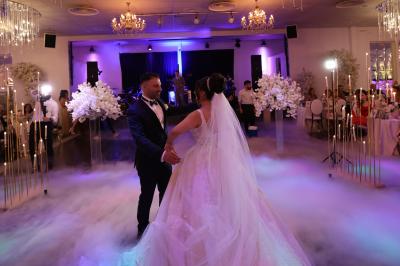 Un groupe de personnes en tenue de cérémonie tient des fumigènes colorés dans un champ ouvert.