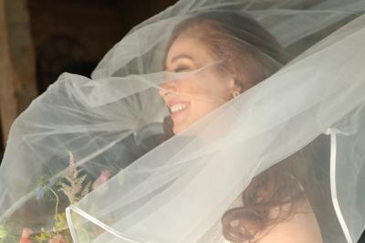 Un groupe de personnes en tenue de cérémonie tient des fumigènes colorés dans un champ ouvert.