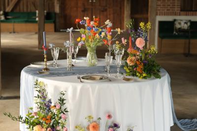 Un groupe de personnes en tenue de cérémonie tient des fumigènes colorés dans un champ ouvert.