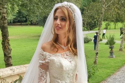 Un groupe de personnes en tenue de cérémonie tient des fumigènes colorés dans un champ ouvert.