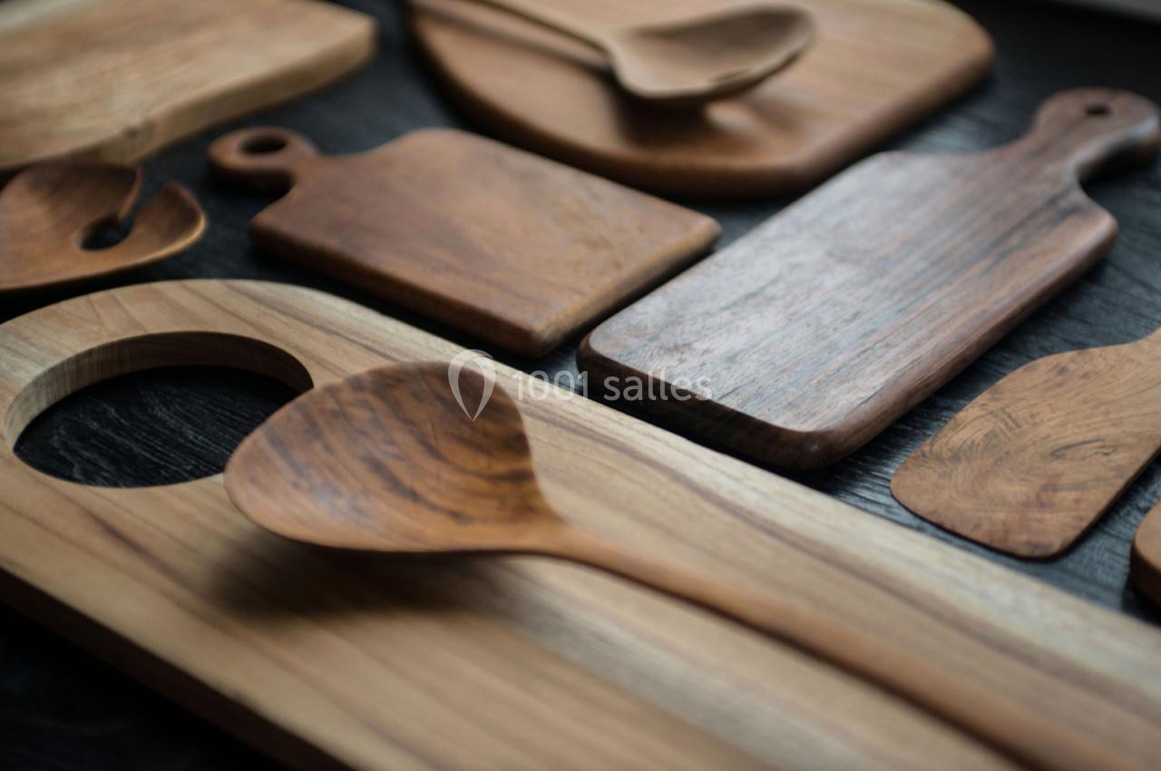 Planchettes et ustensiles en bois disposés sur une surface sombre.