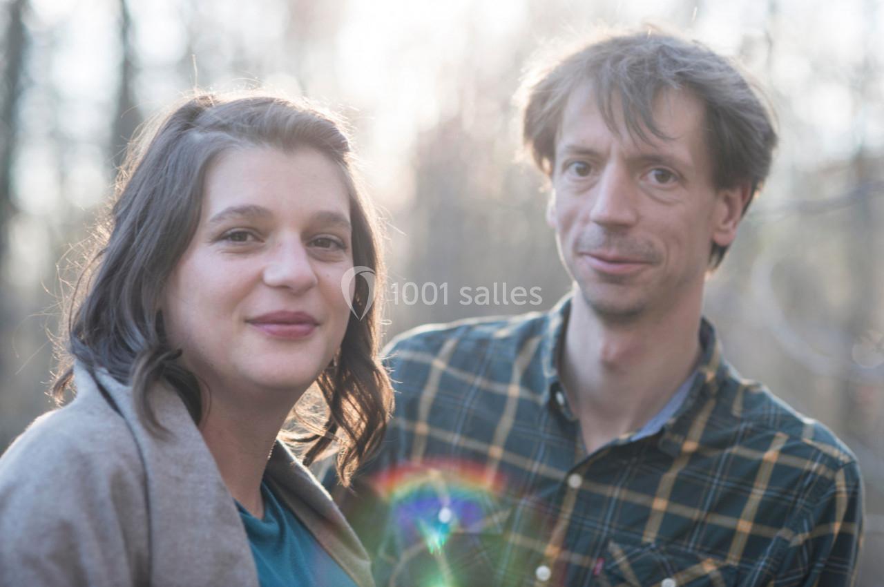 Un homme et une femme posent en extérieur, éclairés par une lumière douce avec un effet de halo coloré.