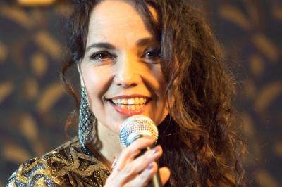 Groupe de musiciens jouant sur scène dans une salle élégante avec un grand lustre et un public dansant.