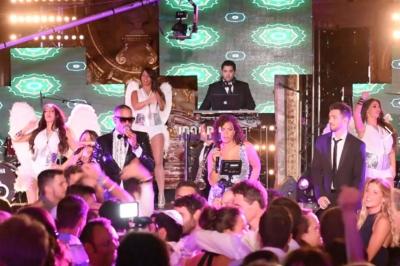 Groupe de musiciens jouant sur scène dans une salle élégante avec un grand lustre et un public dansant.