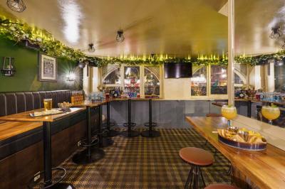 Miniature Location salle Paris 5 (Paris) - Le Pub Saint Michel #3 Salle de restaurant avec banquettes vertes, tables en bois garnies de plats variés et seau à champagne au centre.