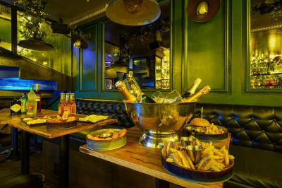 Miniature Location salle Paris 5 (Paris) - Le Pub Saint Michel #14 Salle de restaurant avec banquettes vertes, tables en bois garnies de plats variés et seau à champagne au centre.