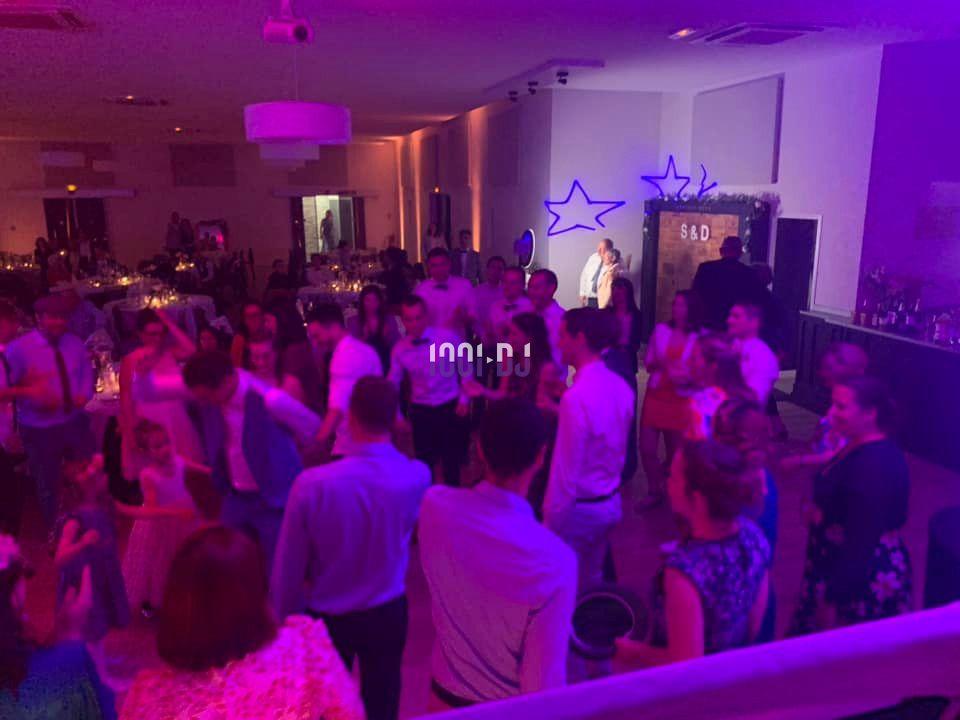 Des personnes dansent dans une salle éclairée par des lumières colorées lors d'un événement festif.