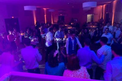 Un DJ mixant de la musique sur une table de mixage dans une salle éclairée par des lumières violettes.