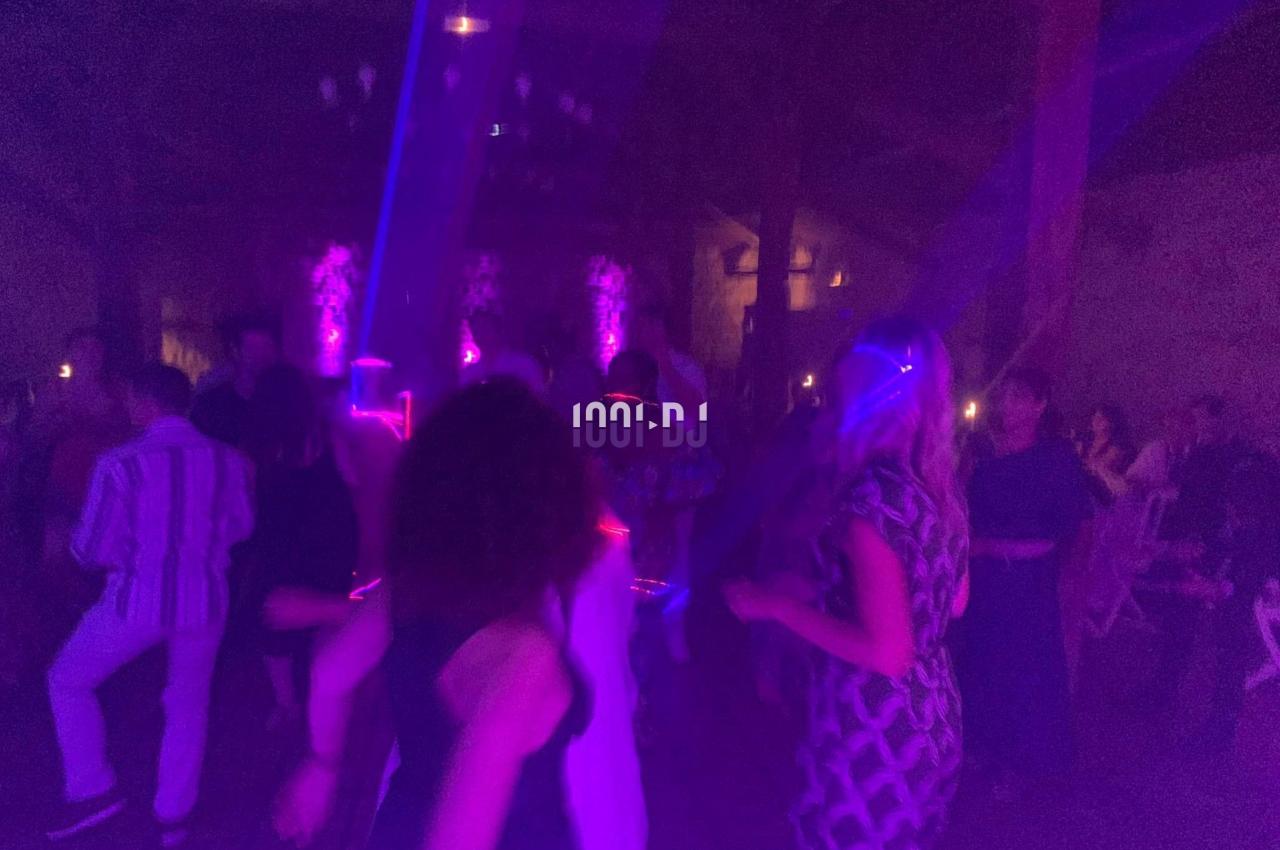 Des personnes dansent dans une ambiance sombre avec des lumières colorées et des effets lumineux.