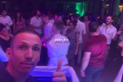 Un DJ mixant de la musique sur une table de mixage dans une salle éclairée par des lumières violettes.