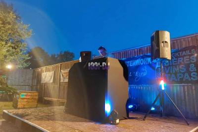 Un DJ mixant de la musique sur une table de mixage dans une salle éclairée par des lumières violettes.