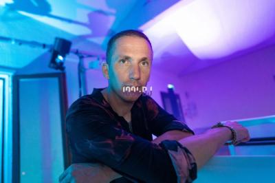 Un DJ mixant de la musique sur une table de mixage dans une salle éclairée par des lumières violettes.