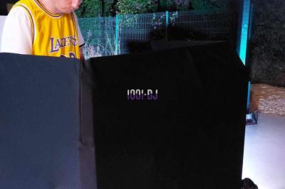 Un DJ mixant de la musique sur une table de mixage dans une salle éclairée par des lumières violettes.