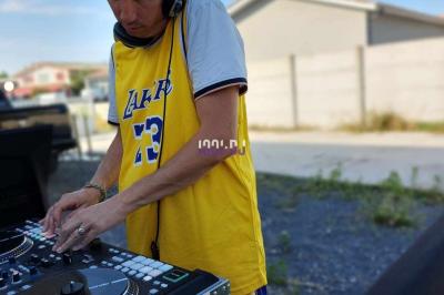 Un DJ mixant de la musique sur une table de mixage dans une salle éclairée par des lumières violettes.