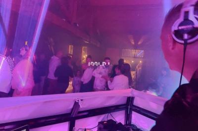 Un DJ mixant de la musique sur une table de mixage dans une salle éclairée par des lumières violettes.