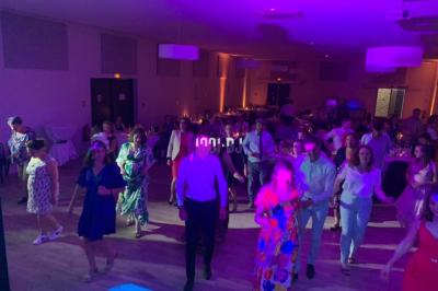 Un DJ mixant de la musique sur une table de mixage dans une salle éclairée par des lumières violettes.