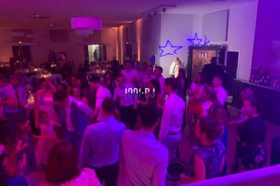 Un DJ mixant de la musique sur une table de mixage dans une salle éclairée par des lumières violettes.