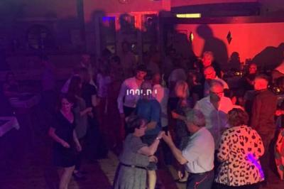 Un DJ mixant de la musique sur une table de mixage dans une salle éclairée par des lumières violettes.