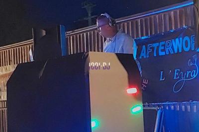 Un DJ mixant de la musique sur une table de mixage dans une salle éclairée par des lumières violettes.